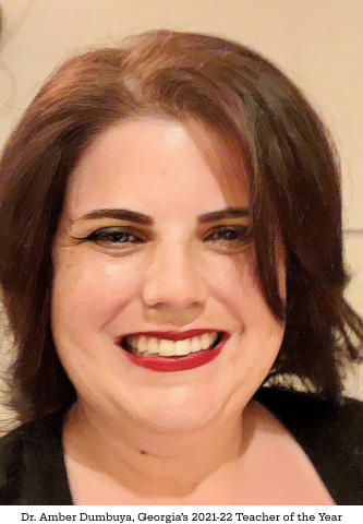 Dr. Amber Dumbuya, with shoulder-length brown hair, smiles broadly in bright red lipstick and a black top.