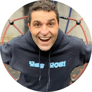 A circular profile image of an enthusiastic man with curly hair smiling widely while wearing a black hoodie with blue text. A red molecular or atomic structure appears in the background.