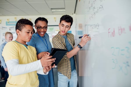 Students working together at a whiteboard to solve a math problem Students working together at a whiteboard to solve a math problem