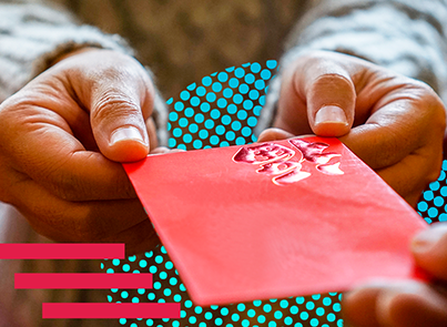 Close-up of hands presenting a traditional red envelope